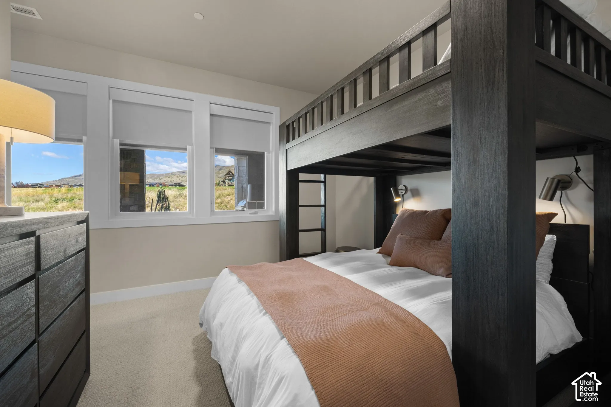 Large windows with white trim framing natural landscape, neutral wall-to-wall carpeting, and recessed lighting