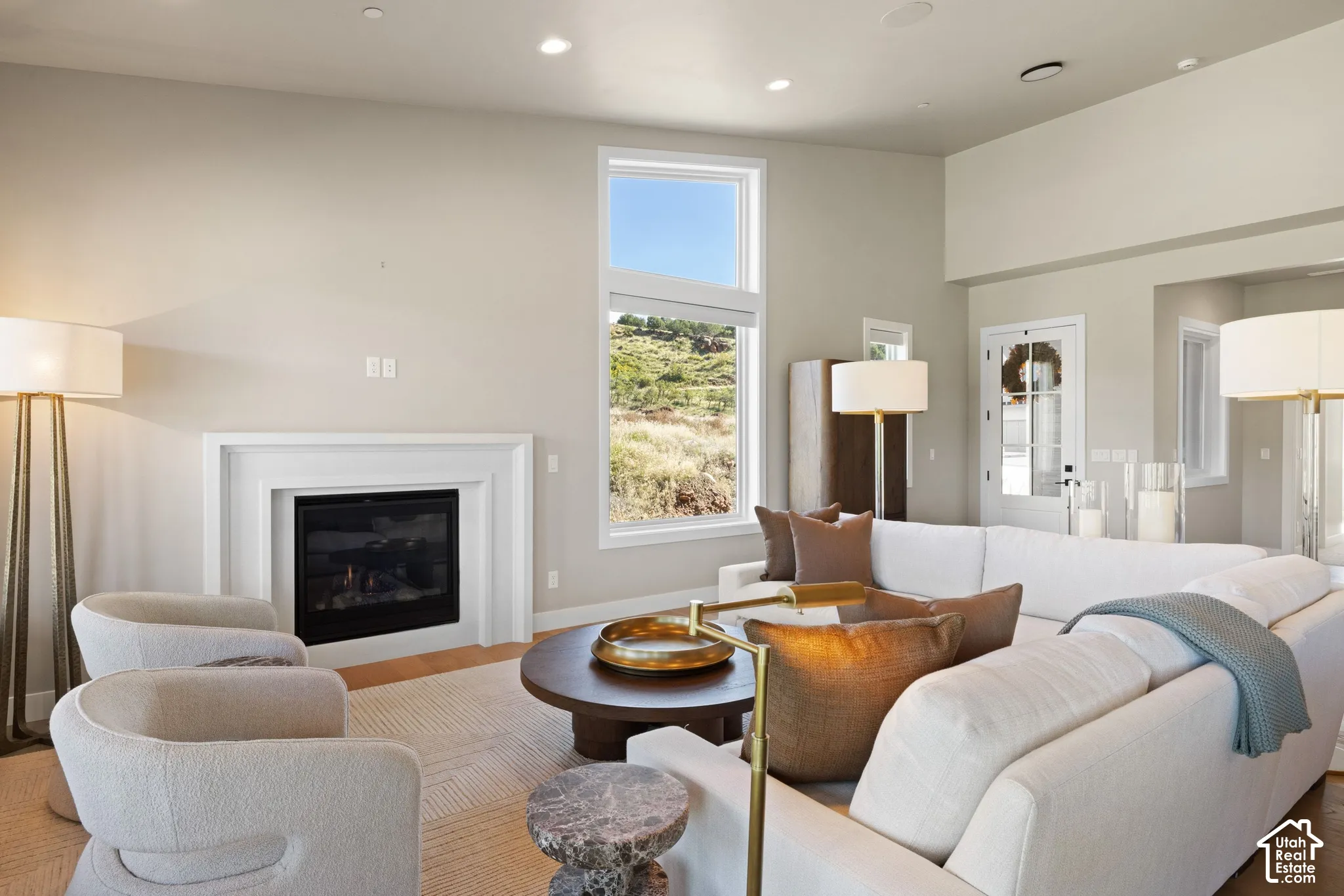 Living area featuring vaulted ceilings, a built-in fireplace with a layered mantle, large-scale windows, and recessed lighting
