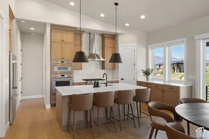Kitchen featuring a quartz-topped central island, stainless steel built-in oven and microwave, stone-finish backsplash, wood-finish cabinetry, and matte black pendant lighting