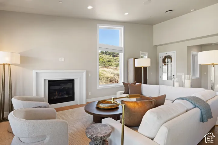 Living area featuring vaulted ceilings, a built-in fireplace with a layered mantle, large-scale windows, and recessed lighting