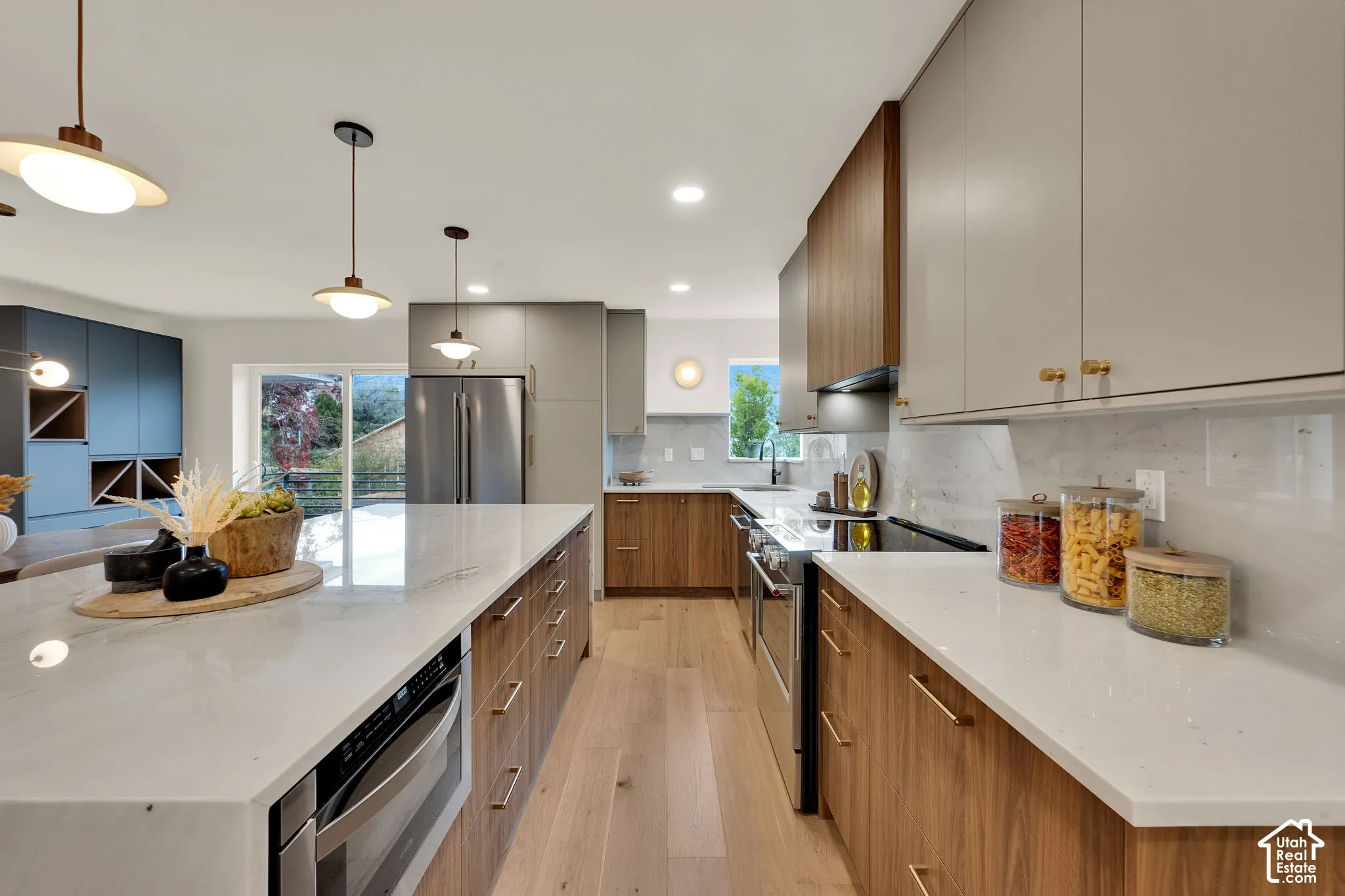 Kitchen featuring wood-finish cabinetry, quartz countertops, stainless steel appliances, wood flooring, and pendant lighting