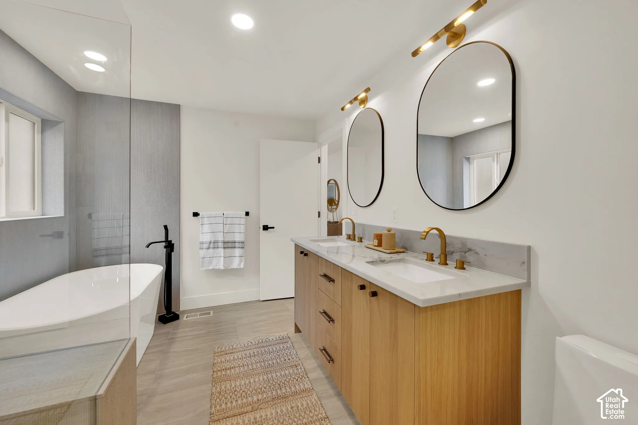Primary bathroom featuring a dual-sink vanity with stone countertop