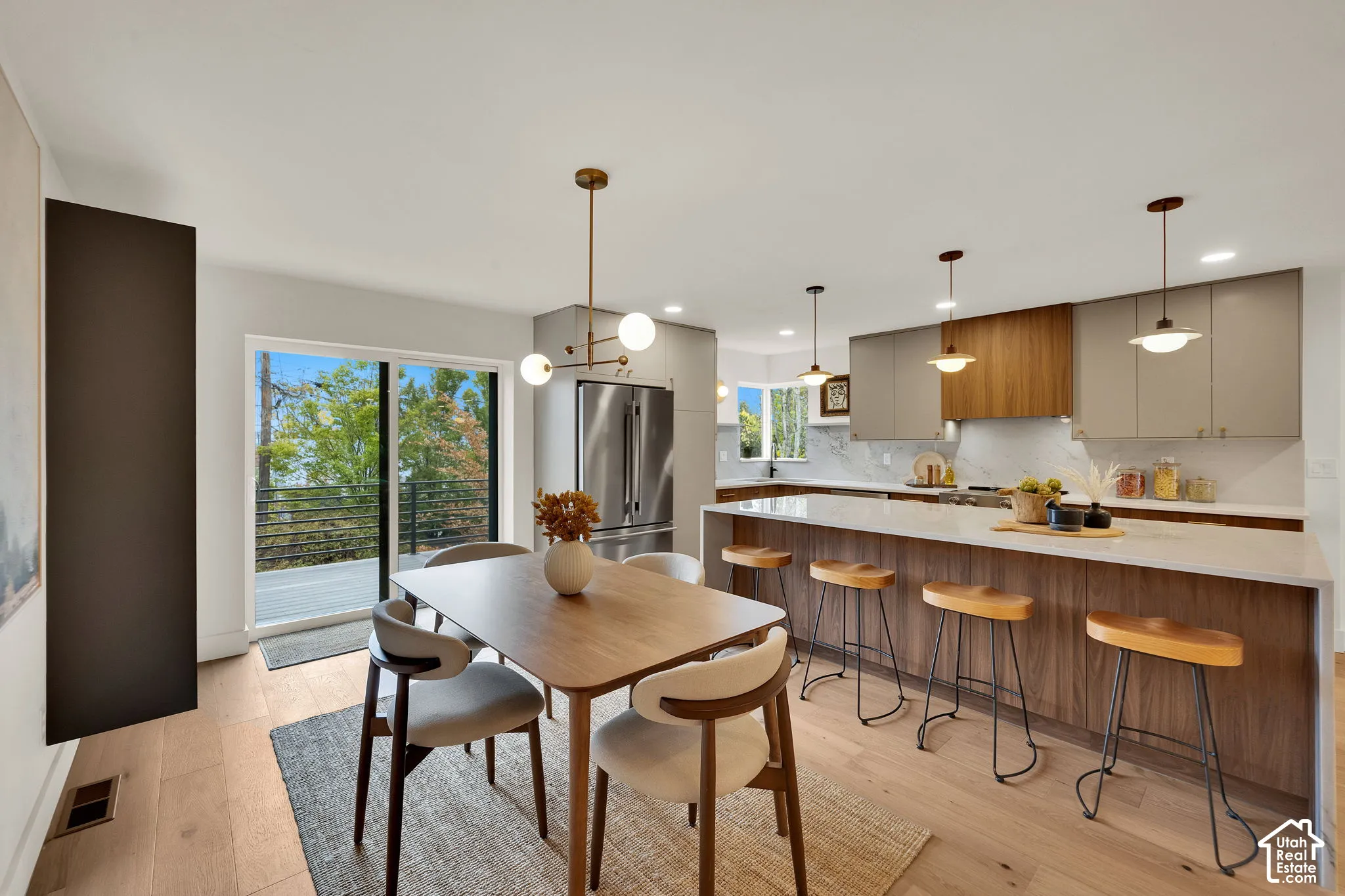 Kitchen featuring flat-panel cabinetry, a wood-accent range hood, quartz countertops, a waterfall-edge island, and wood flooring