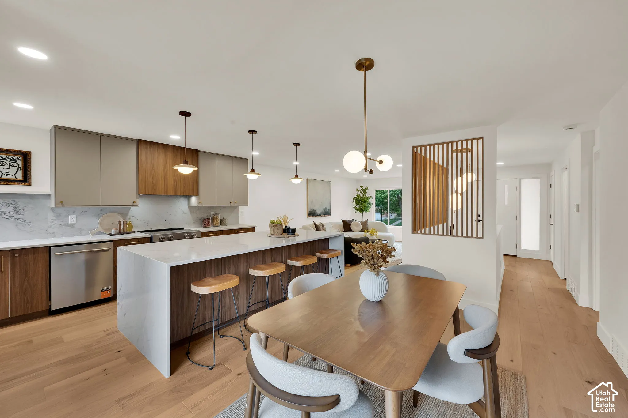 Kitchen featuring dual-tone cabinetry, expansive waterfall-edge island, wood flooring, and decorative vertical slat room partition
