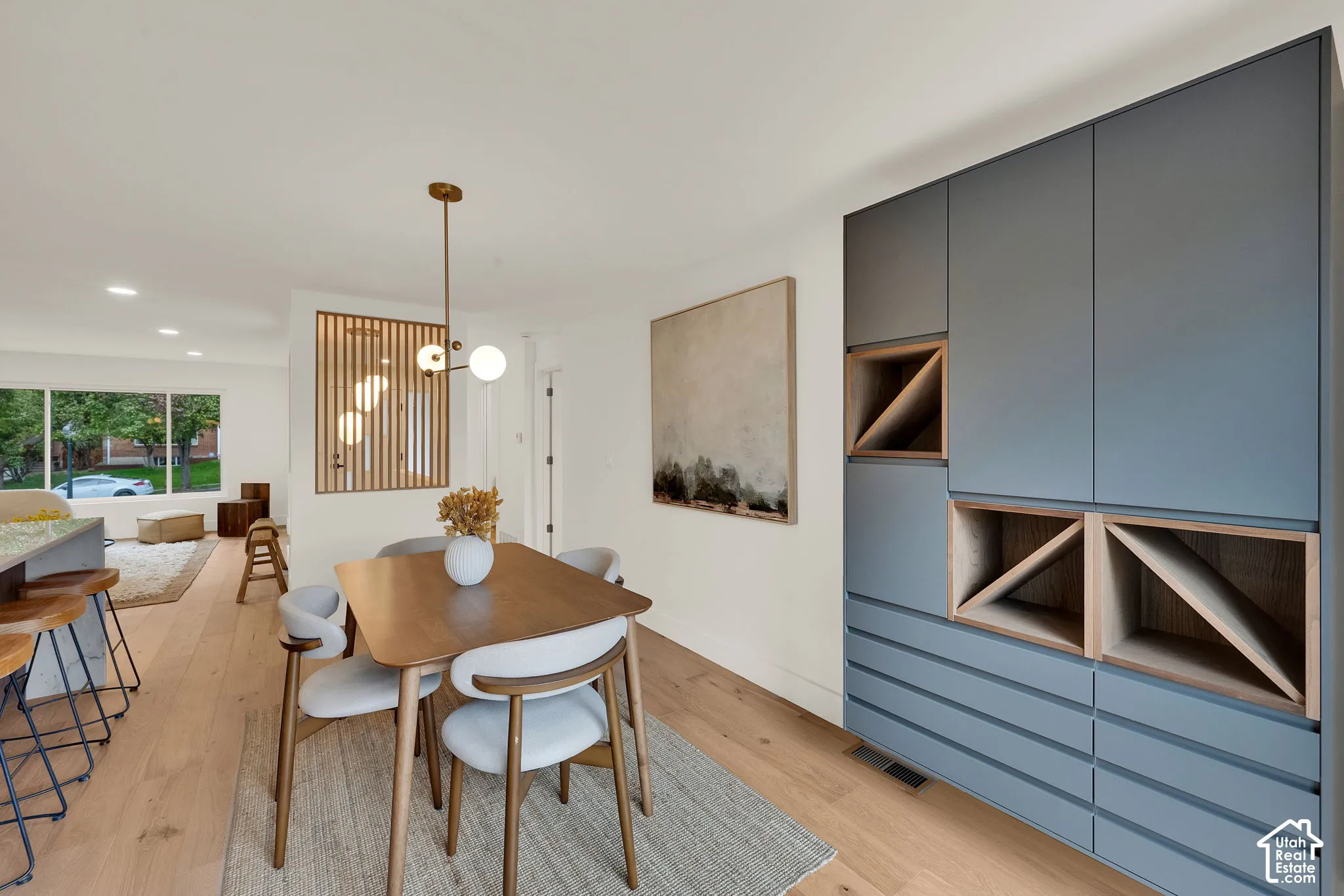 Custom cabinetry with integrated wood-toned shelving, light wood flooring, recessed lighting, and a vertical wood slat partition