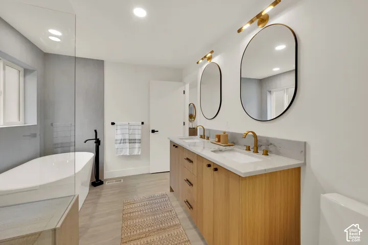 Primary bathroom featuring a dual-sink vanity with stone countertop