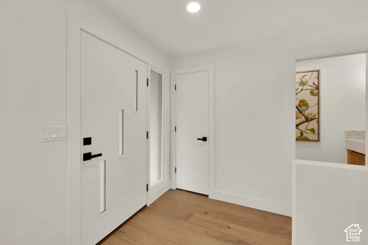 Entryway featuring a solid white door with rectangular glass insets, wood flooring, recessed lighting, and matte black door hardware