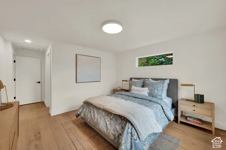 Primary bedroom featuring light-toned wood flooring, a horizontal window, and a minimalist flush-mount ceiling fixture