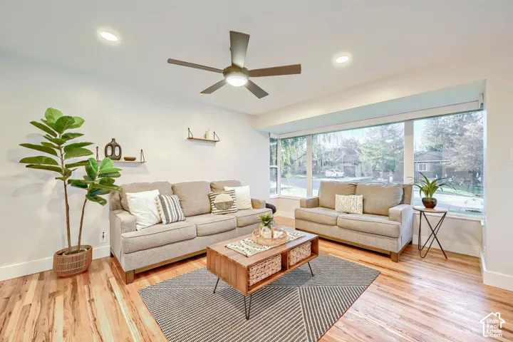 Living area featuring wood-finish flooring, a large multi-pane window, recessed lighting, and a ceiling fan