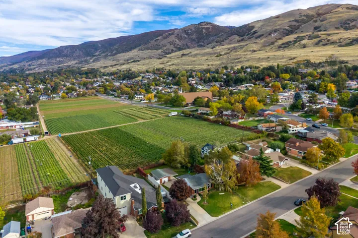 Aerial perspective featuring a multi-story residence with a dark-toned gable roof, a detached garage, and mature trees set against a mountain backdrop