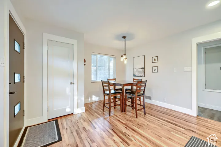Entryway featuring wood-finish flooring, a contemporary three-light pendant fixture, white door and trim, and a multi-paneled exterior door with glass inserts