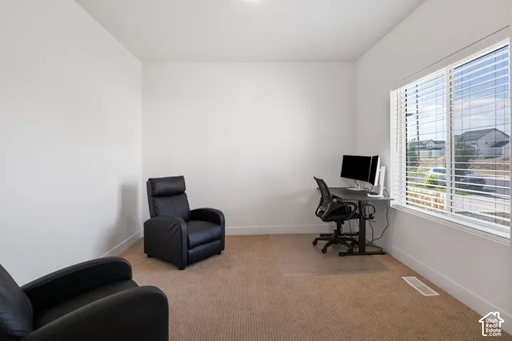 Neutral-toned carpeted room featuring expansive windows with installed blinds and natural lighting