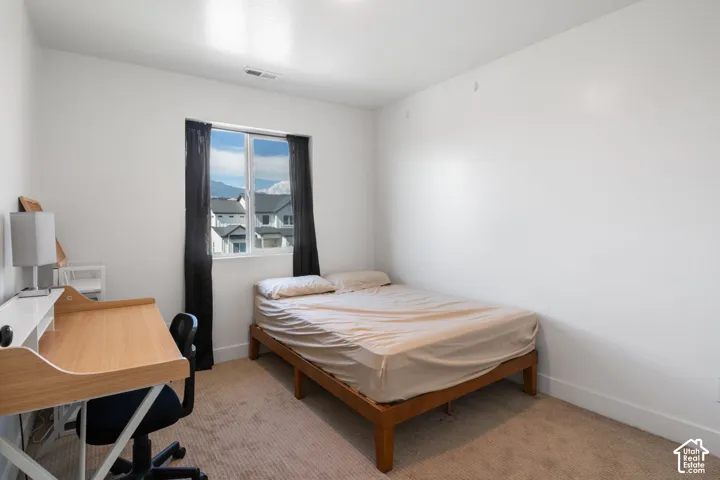 Neutral-toned interior space featuring light-toned carpeted flooring, white walls, and a single-pane window