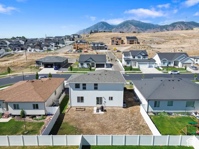 Aerial perspective featuring a two-story home, white vinyl perimeter fencing, and prominent mountain backdrop