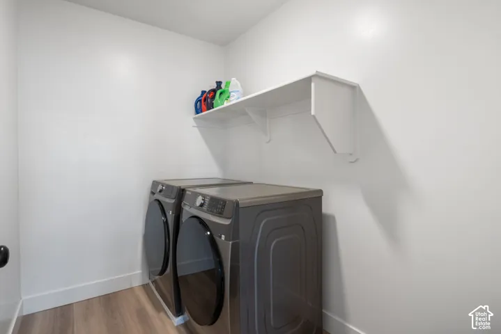 Laundry area featuring wood-finish flooring and a white wall-mounted shelf