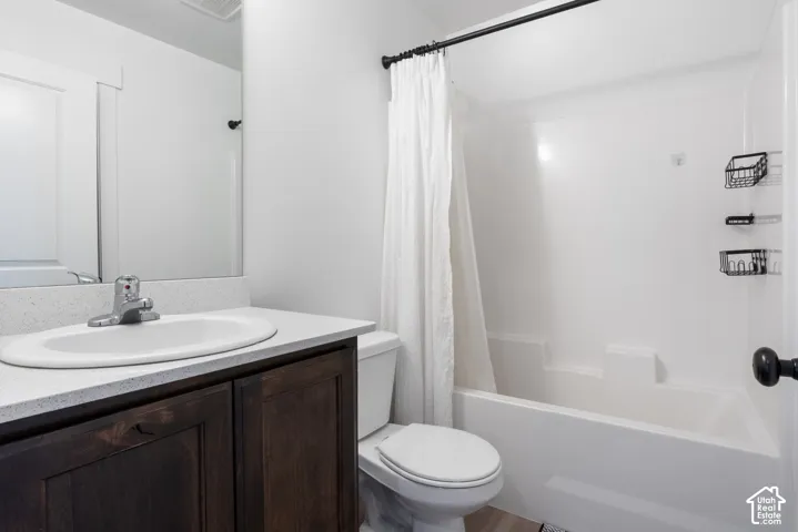 Bathroom featuring a dark wood-finish vanity, light-toned solid surface countertop with an integrated oval basin, large wall-mounted mirror, and a tub-shower combination with a surround