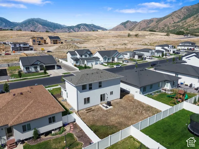 Two-story residence featuring a white exterior, hip roof, paved patio, and mountain backdrop