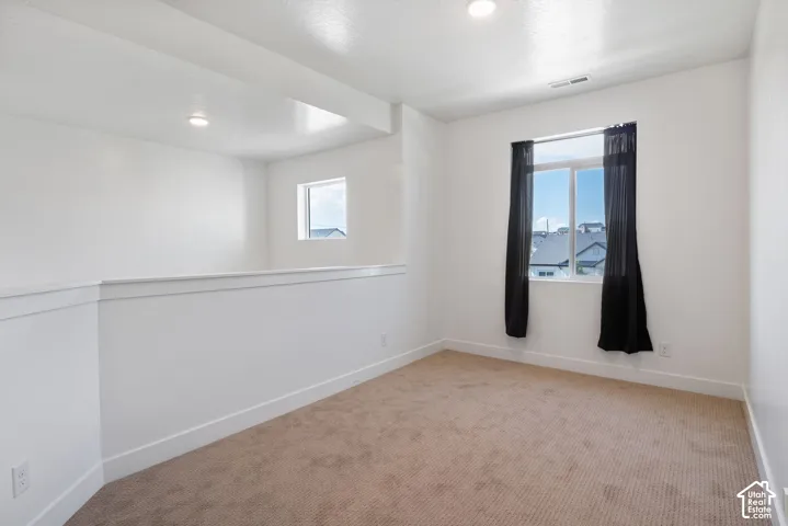 Neutral-toned carpeted flooring, dual-pane windows, recessed ceiling lighting, and crisp white wall finishes