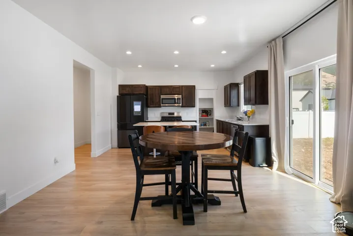 Kitchen featuring dark wood cabinetry, light-toned countertops, wood-finish flooring, recessed lighting, and sliding glass doors