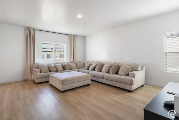Neutral-toned interior space featuring wood-finish flooring, recessed lighting, and large windows with horizontal blinds