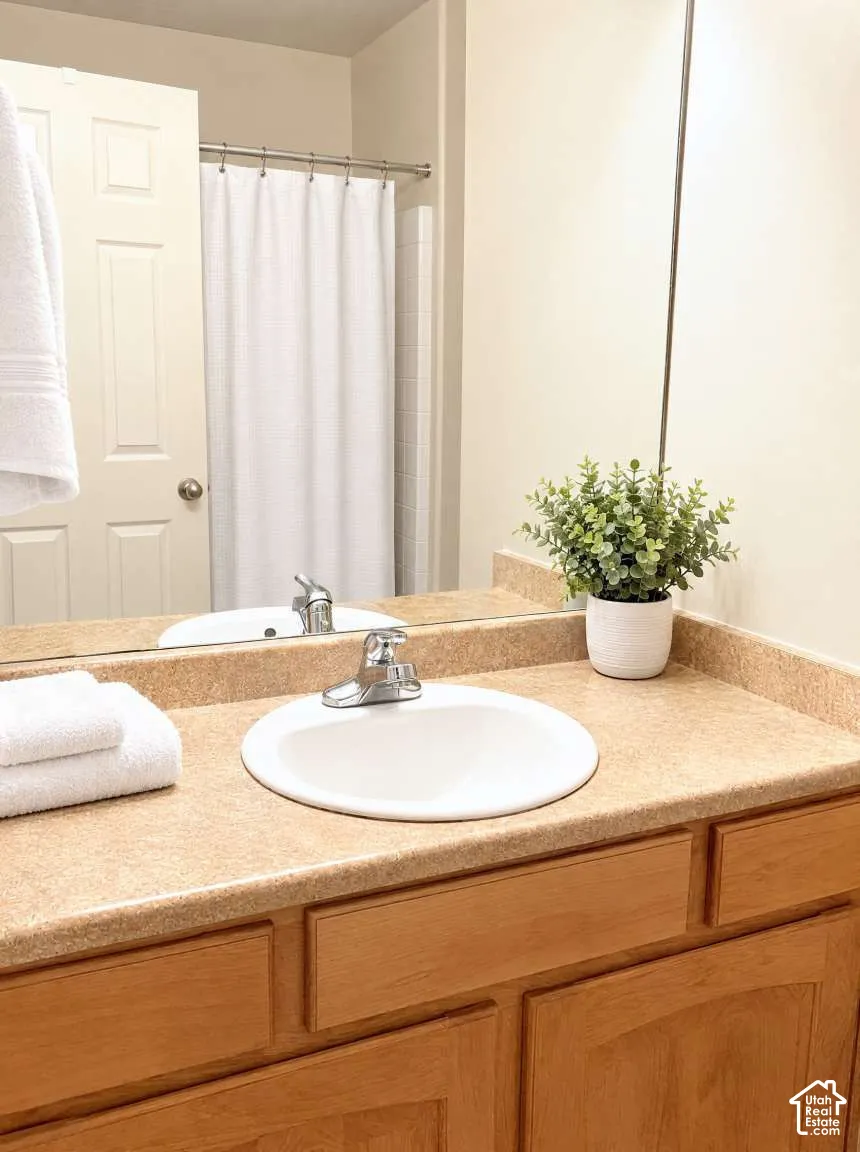 Bathroom vanity featuring a natural wood-finish cabinet, integrated countertop with a matching backsplash, undermount sink, and polished metal faucet hardware