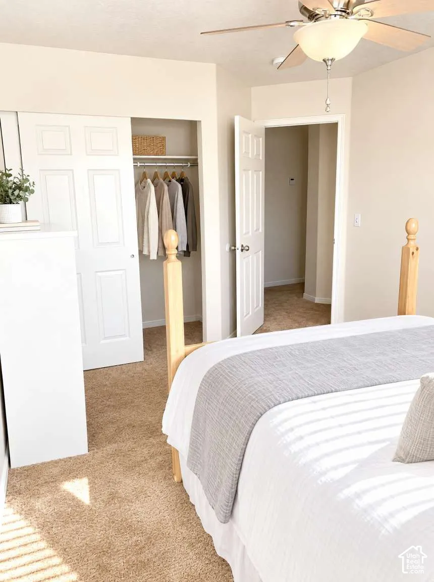 Neutral wall coloring, wall-to-wall carpeting, white paneled closet doors, and a ceiling fan with integrated lighting fixture