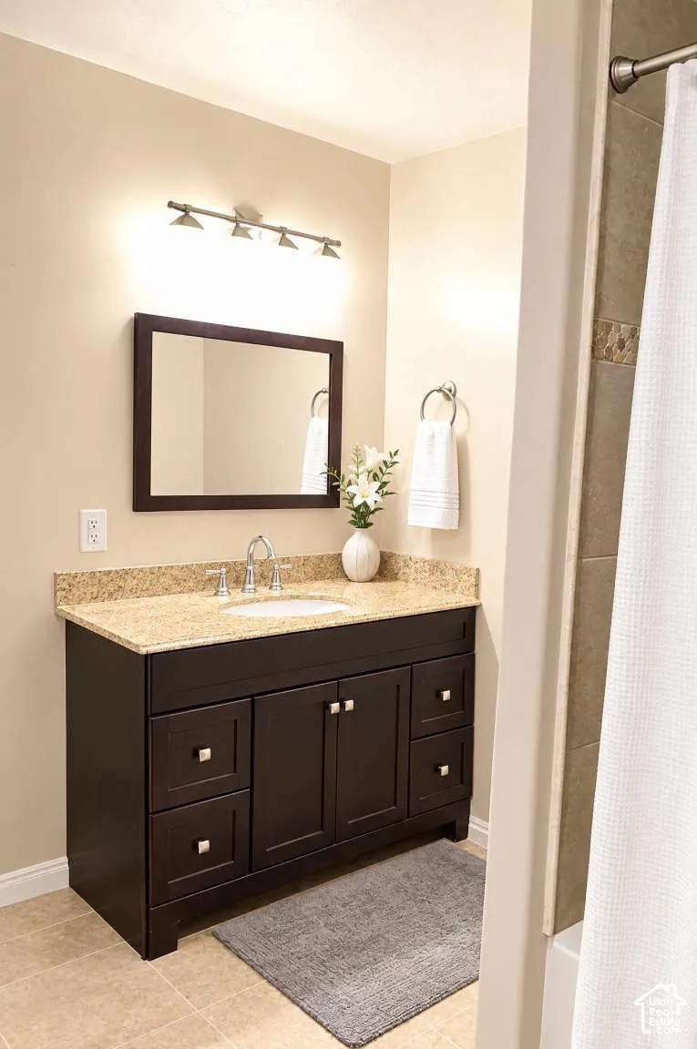 Dark wood vanity featuring a stone countertop, an integrated undermount sink, a framed mirror, and a multi-light fixture