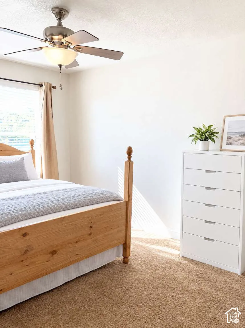 Neutral-toned carpet flooring, multi-blade ceiling fan with integrated light fixture, and horizontal blind window covering
