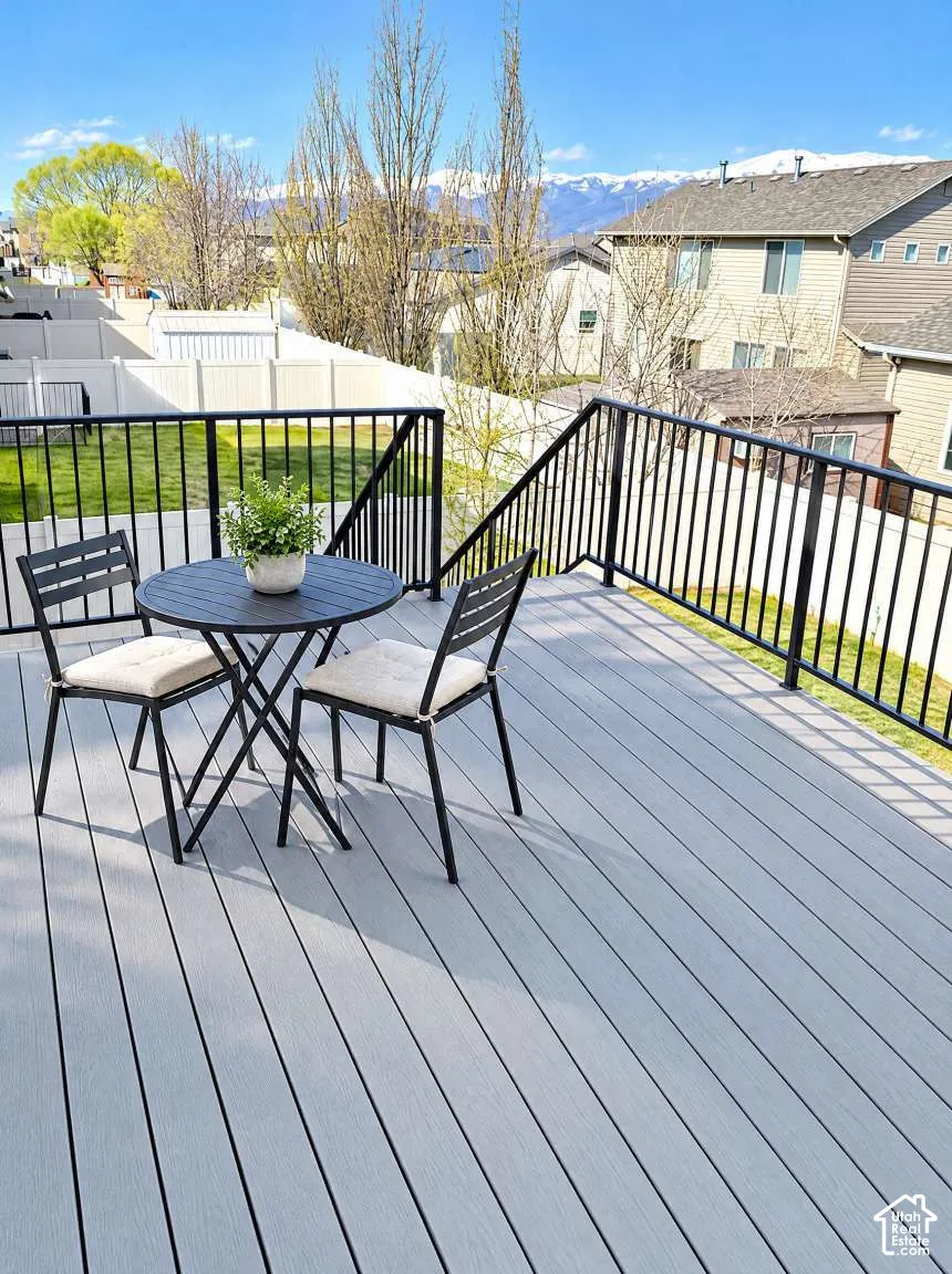 Elevated deck featuring composite plank flooring, black metal railing, and snow-capped mountain scenery