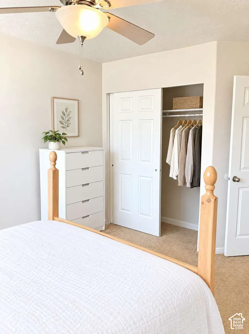 Room featuring neutral wall tones, wall-to-wall carpeting, a ceiling fan with integrated light fixture, and a closet with six-panel sliding doors