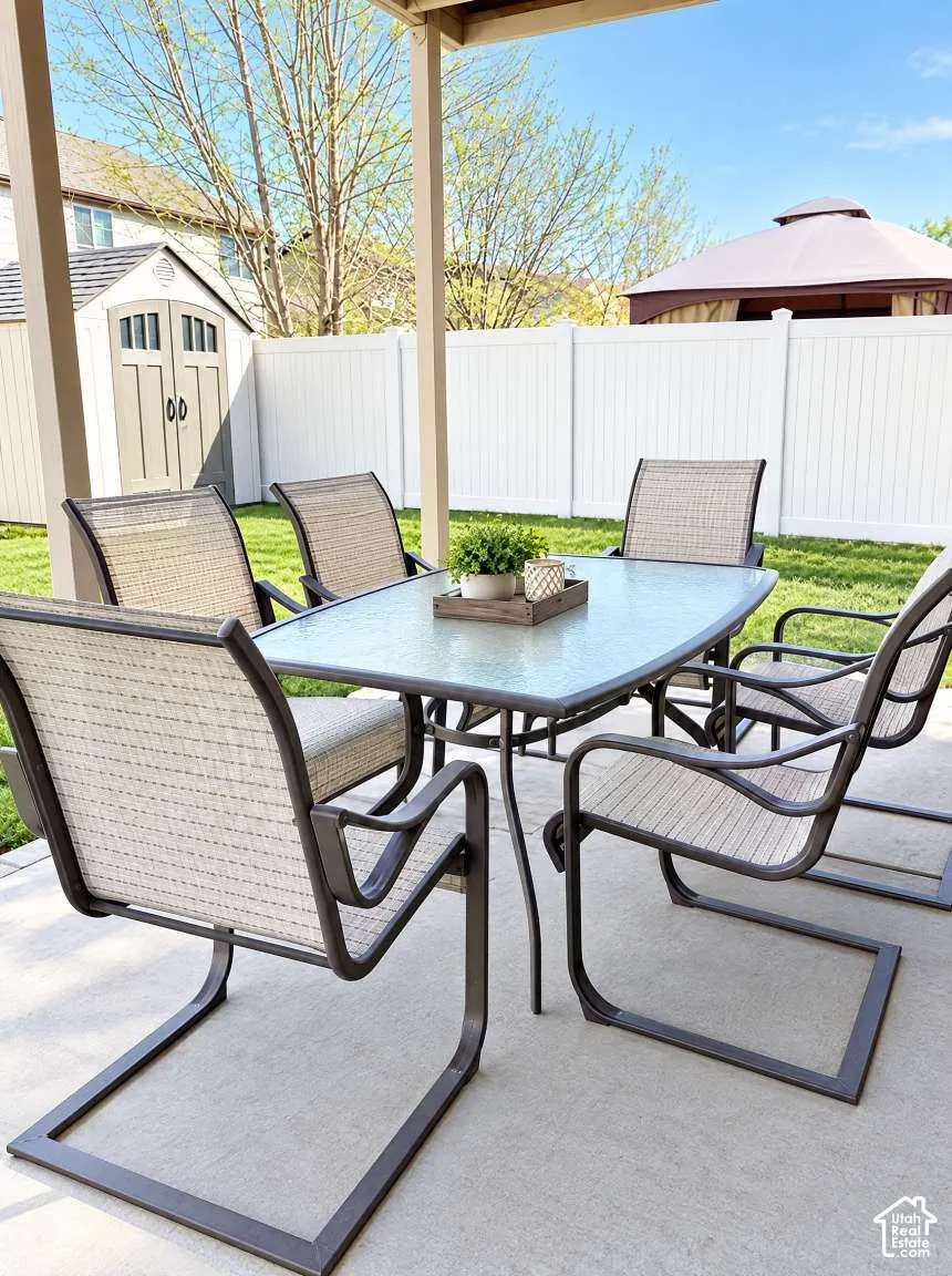 Covered concrete patio featuring a fenced backyard, lawn space, and a detached storage shed