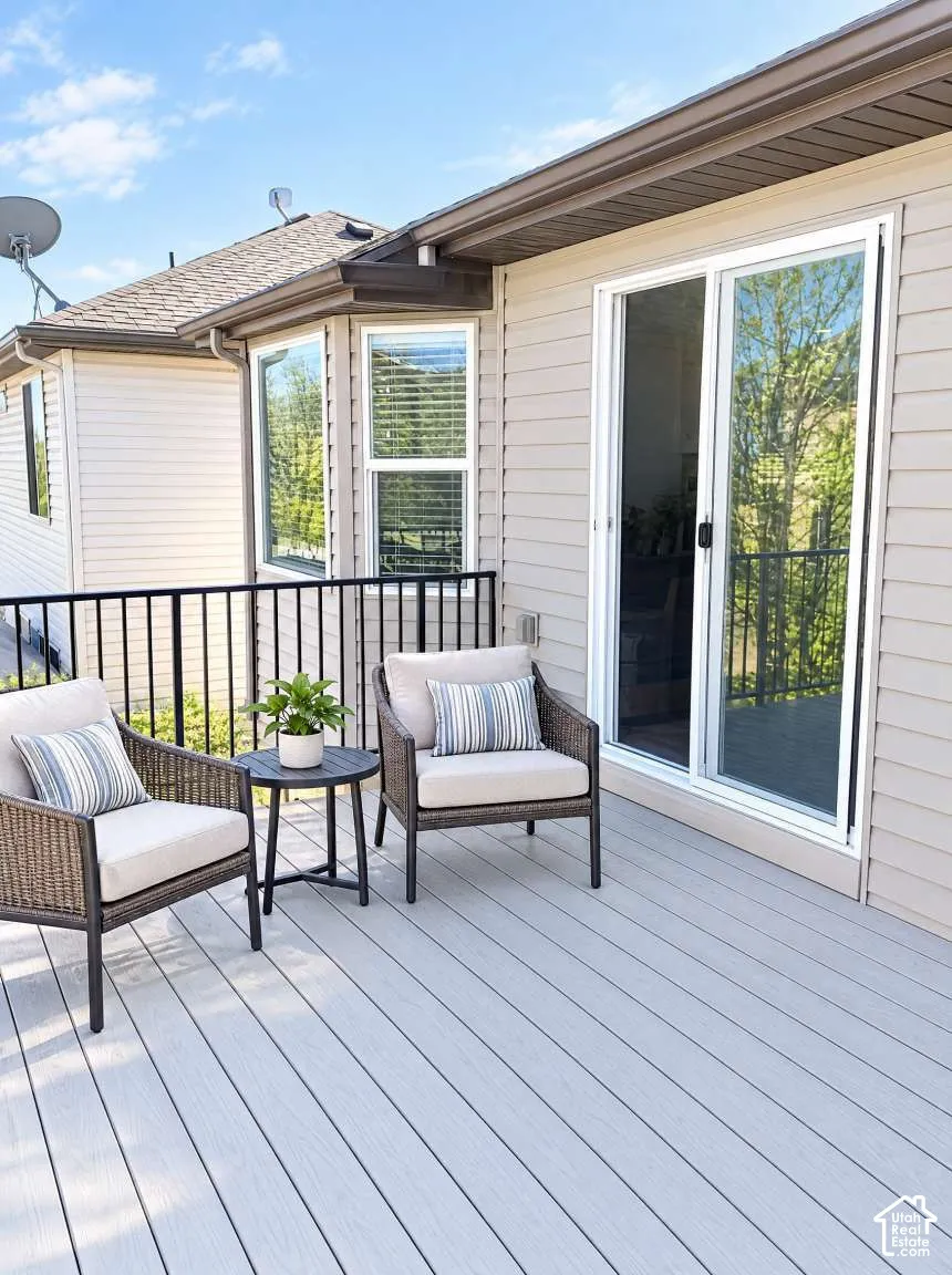 Exterior deck featuring light gray composite decking, black metal railings, siding finish, and sliding glass doors