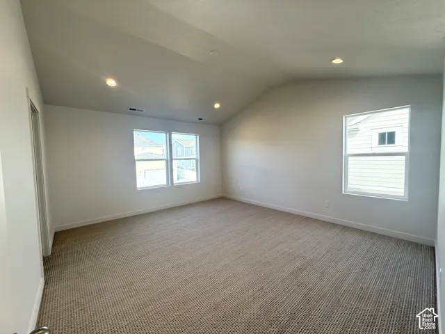 Vaulted ceilings, neutral-toned wall-to-wall carpeting, and recessed lighting throughout