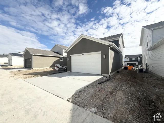 Contemporary exterior featuring a dark stucco finish, white sectional garage door, concrete driveway, and roof with architectural shingles