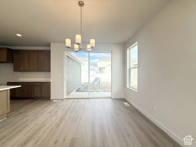 Open-concept space featuring wood-finish flooring, dark wood cabinetry, a five-light chandelier, and large sliding glass doors
