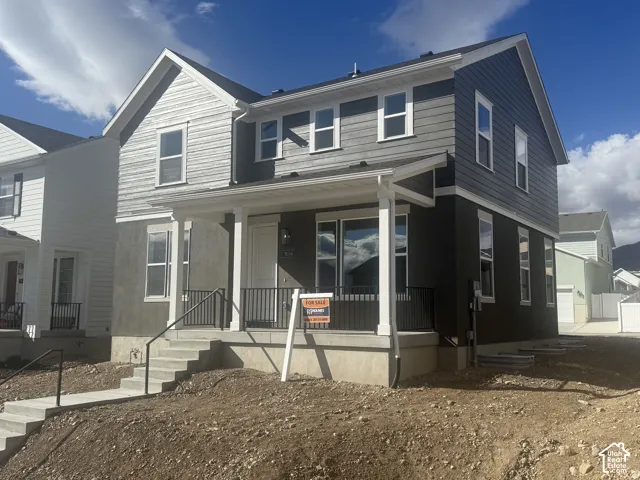 Two-story exterior featuring multi-textured siding, a covered front porch, concrete stairs, and black metal railings