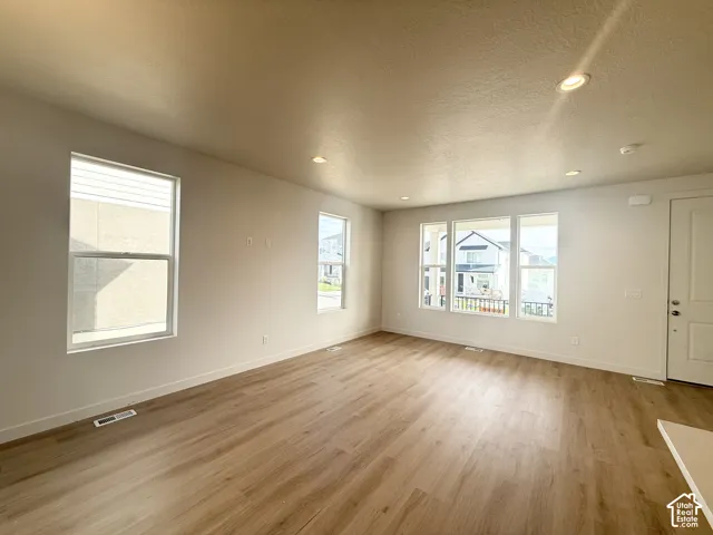 Open-concept room featuring neutral wall paint, wood-finish flooring, recessed lighting, and multiple windows providing natural illumination