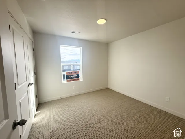 Neutral-toned wall-to-wall carpeting, window with natural lighting, and double-panel interior door with brushed metal hardware