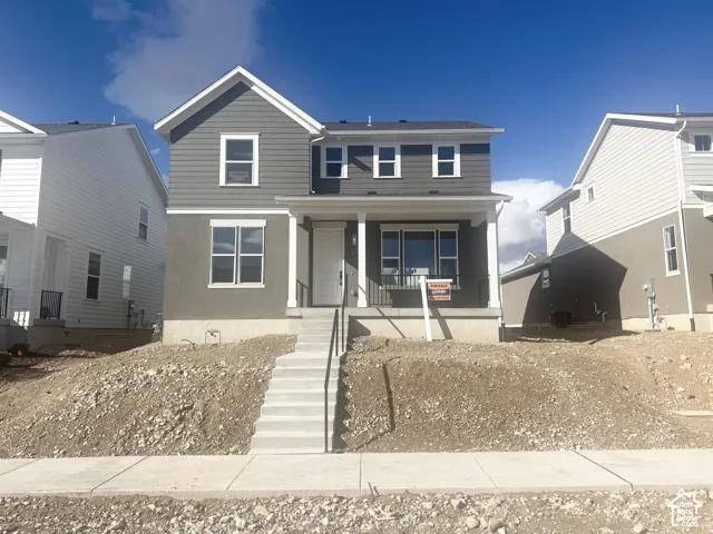 Two-story residence featuring horizontal lap siding, a covered front porch with decorative columns, and concrete steps with black metal handrails