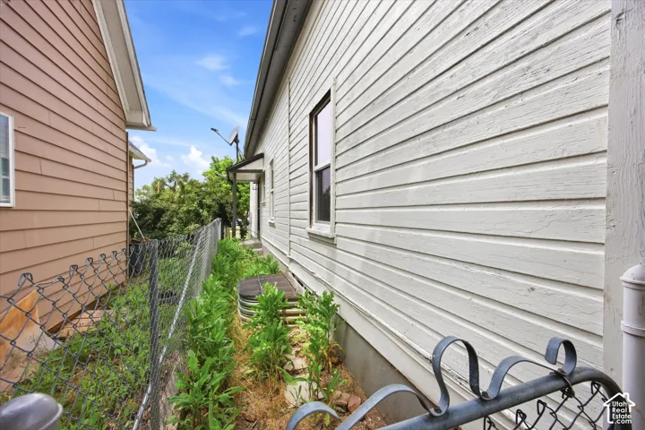 Exterior side elevation featuring horizontal lap siding, a window casing with a single-hung window, and a metal window well cover