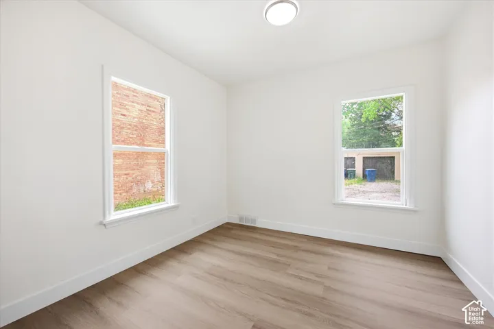 Neutral-toned walls, wood-finish flooring, two dual-pane windows, and a flush-mount overhead light fixture