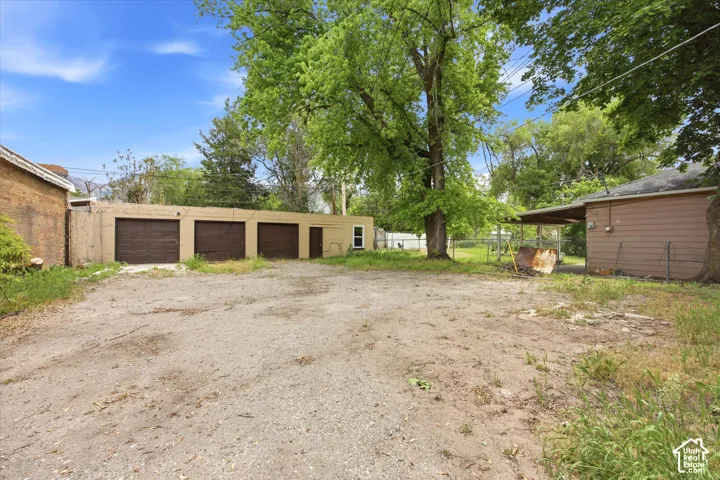 Exterior grounds featuring a detached three-car garage and a covered outdoor structure