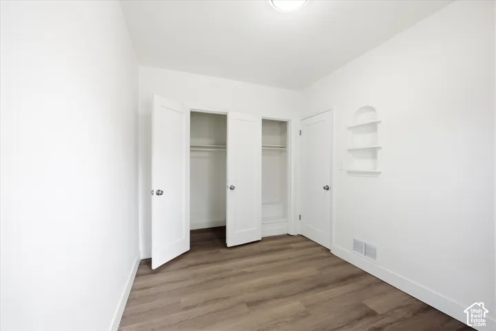 Wood-finish flooring, double-door reach-in closet, and recessed wall shelving