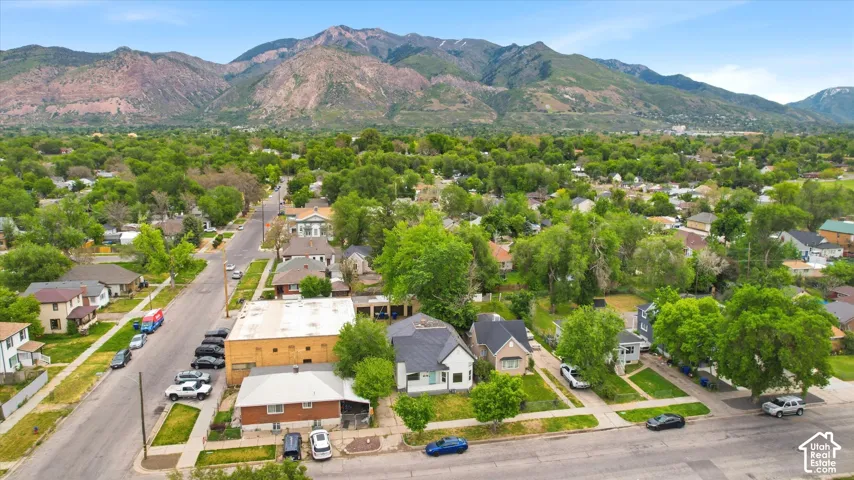 Aerial perspective of the residential property featuring mature trees, landscaped lawns, and prominent mountain backdrops