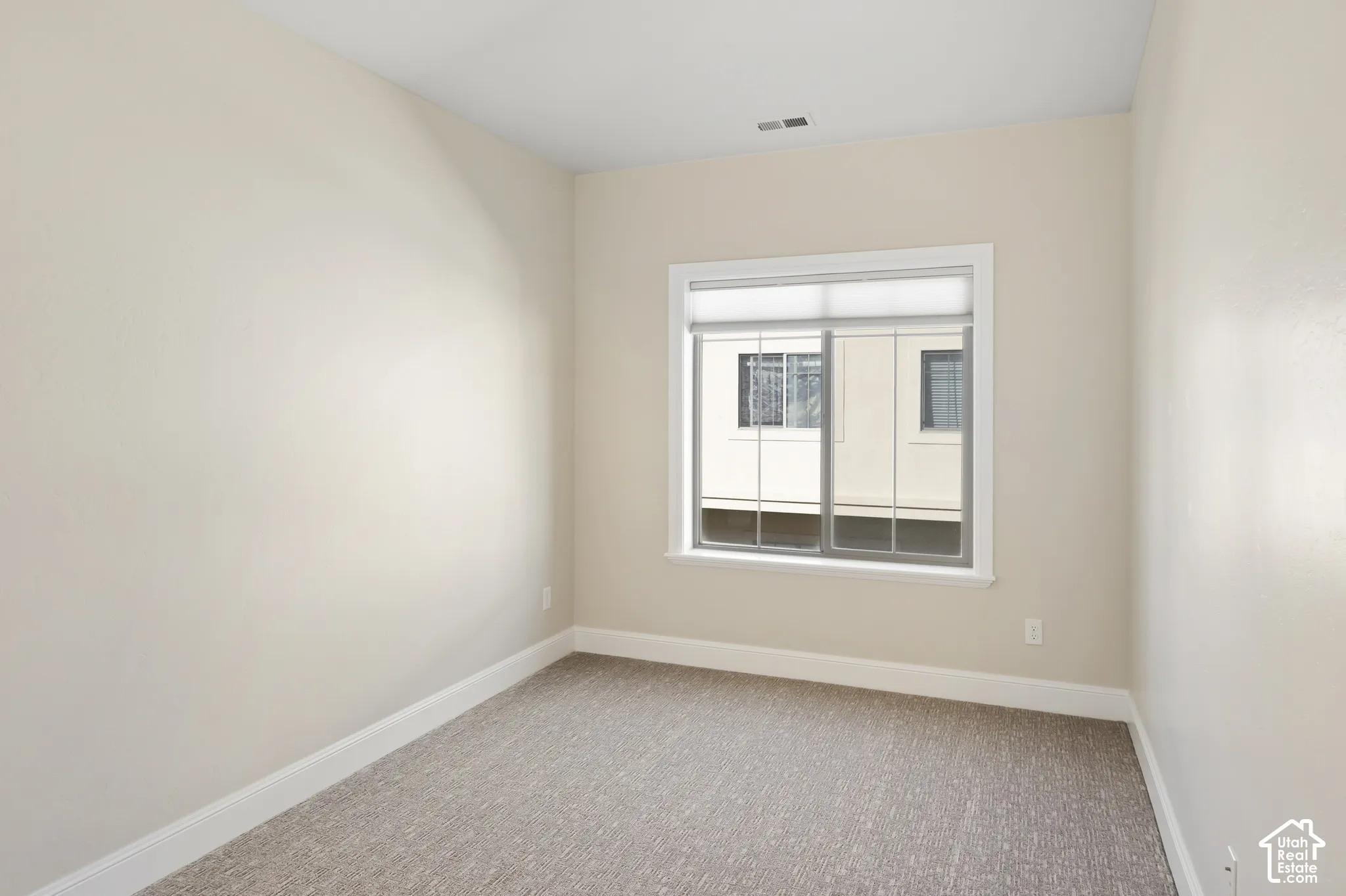 2nd Bedroom with neutral-toned interior space featuring light-colored wall paint, plush carpeting, and a sliding window with installed window treatment