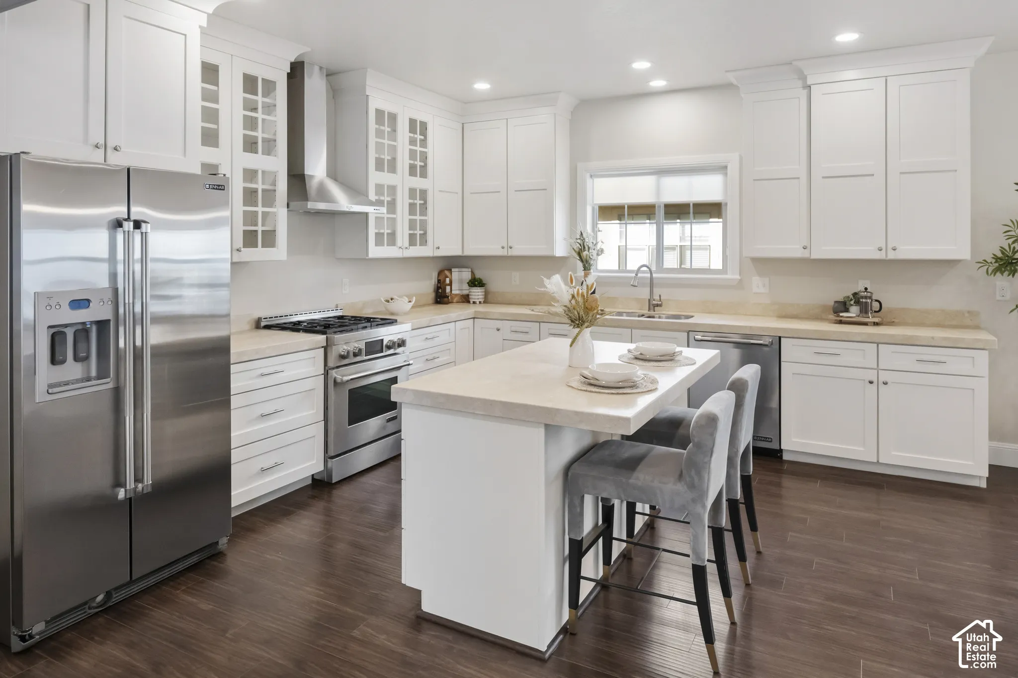 Kitchen featuring white shaker-style cabinetry with honed marble stone-surface countertops, high-end gourmet stainless steel gas appliances, a central island, and wood-finish flooring
