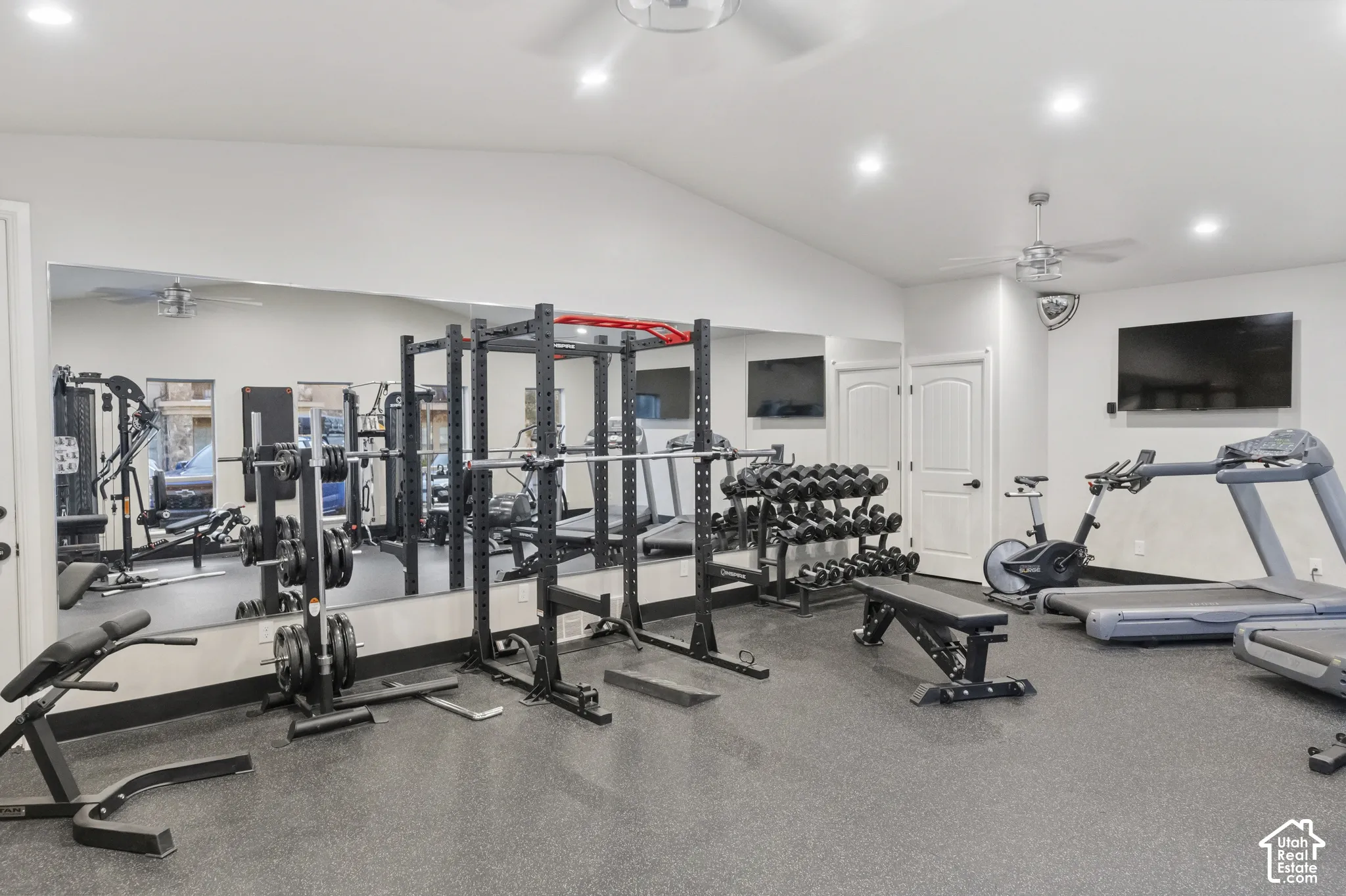Vaulted ceiling with recessed lighting, wall-to-wall mirror, and resilient flooring