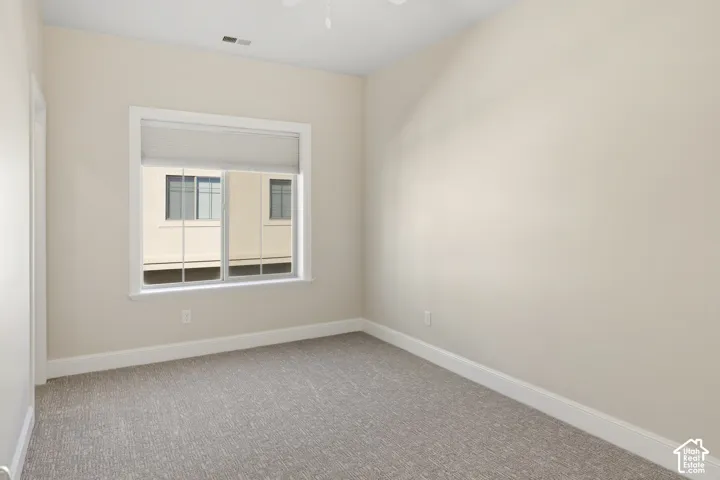 3rd Bedroom with a large walk-in closet featuring neutral wall paint, wall-to-wall carpeting, and a dual-pane sliding window with crisp white trim