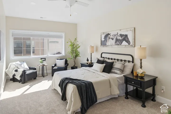 Neutral-toned wall paint, neutral carpeting, oversized window and vaulted ceiling-mounted fan with integrated light fixture