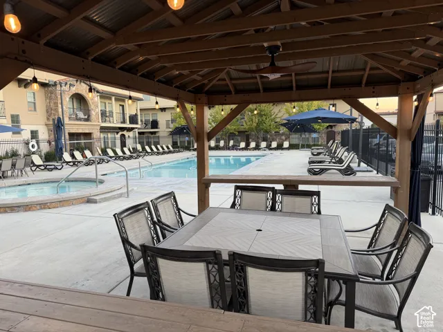 Covered timber-frame pavilion featuring a metal roof, ceiling fan, and string lighting, complemented by a swimming pool, integrated spa, and concrete deck